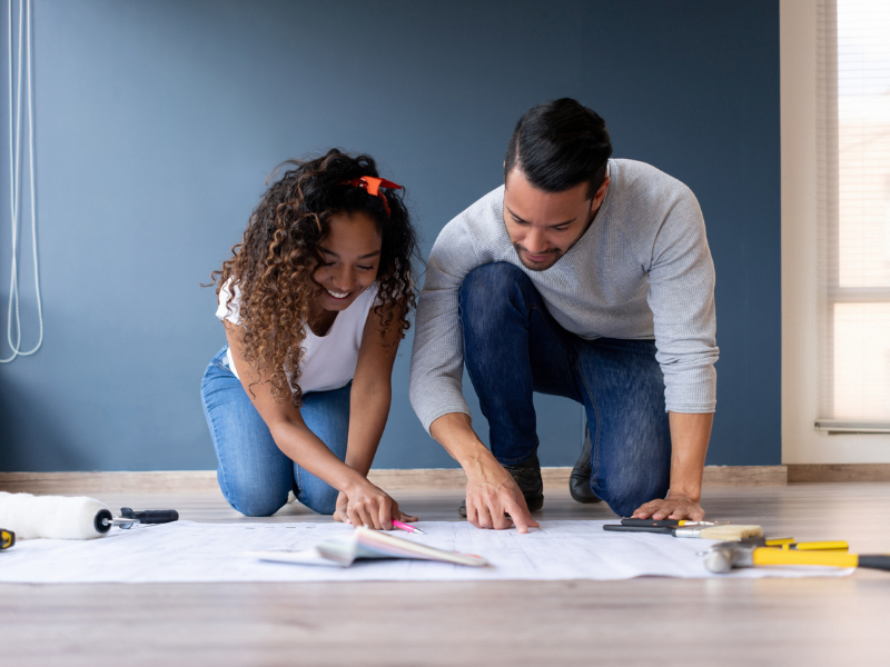A man and a woman look at their home renovation blueprints.